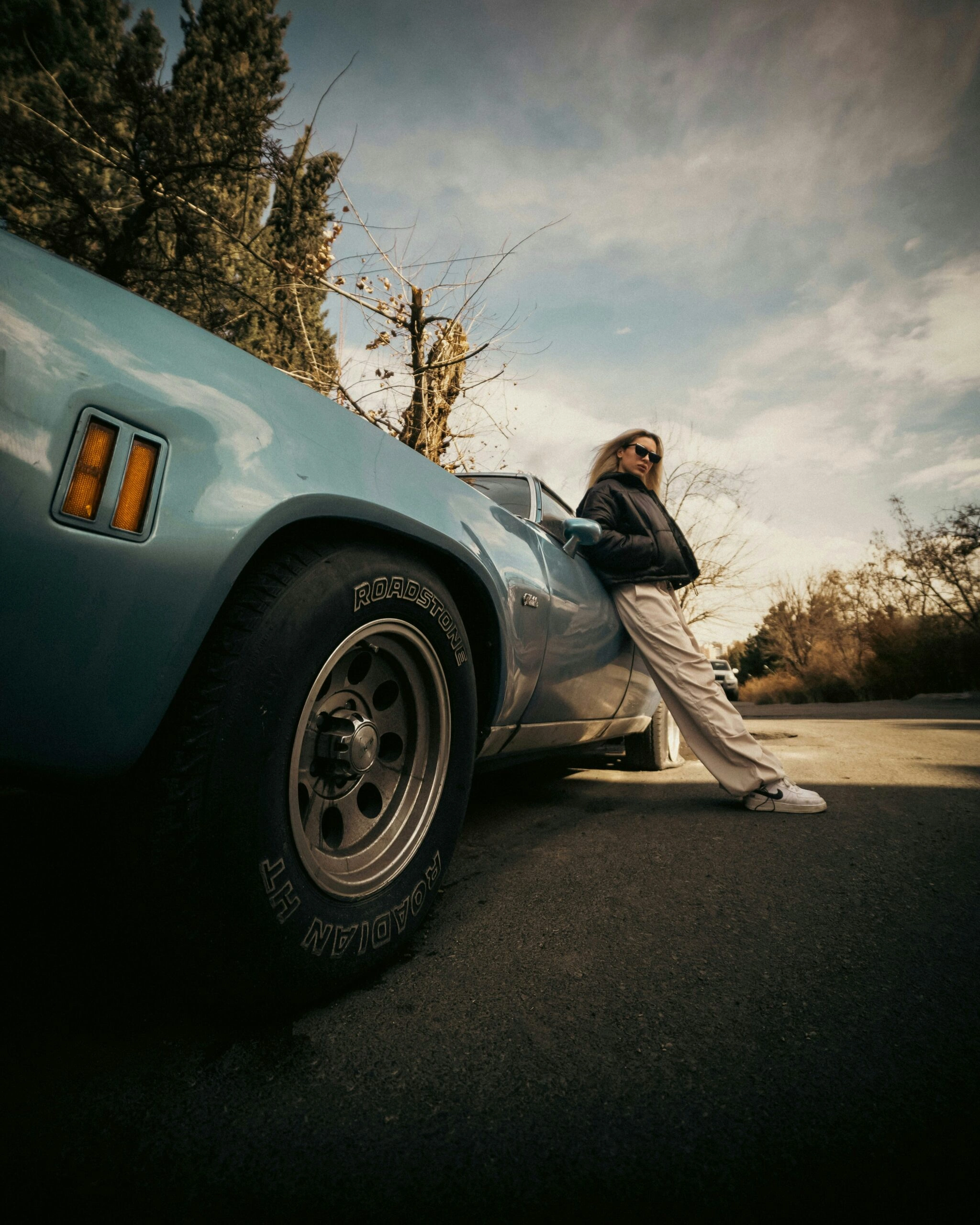 Woman leaning against a vintage car before a road trip — accompanying the FAQ section for the Build Your Custom GPT workshop