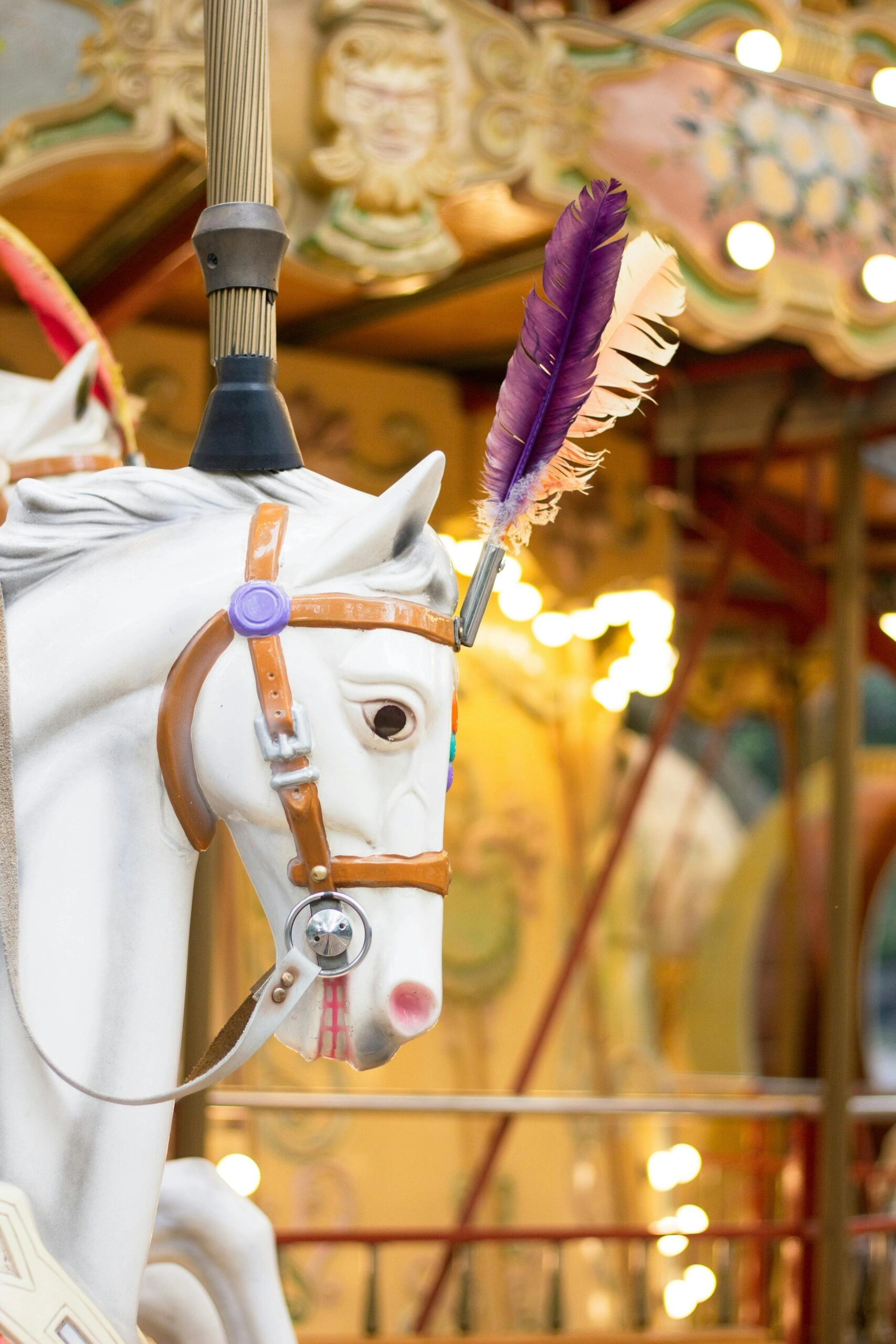 White carousel horse with feathers on a lit merry-go-round