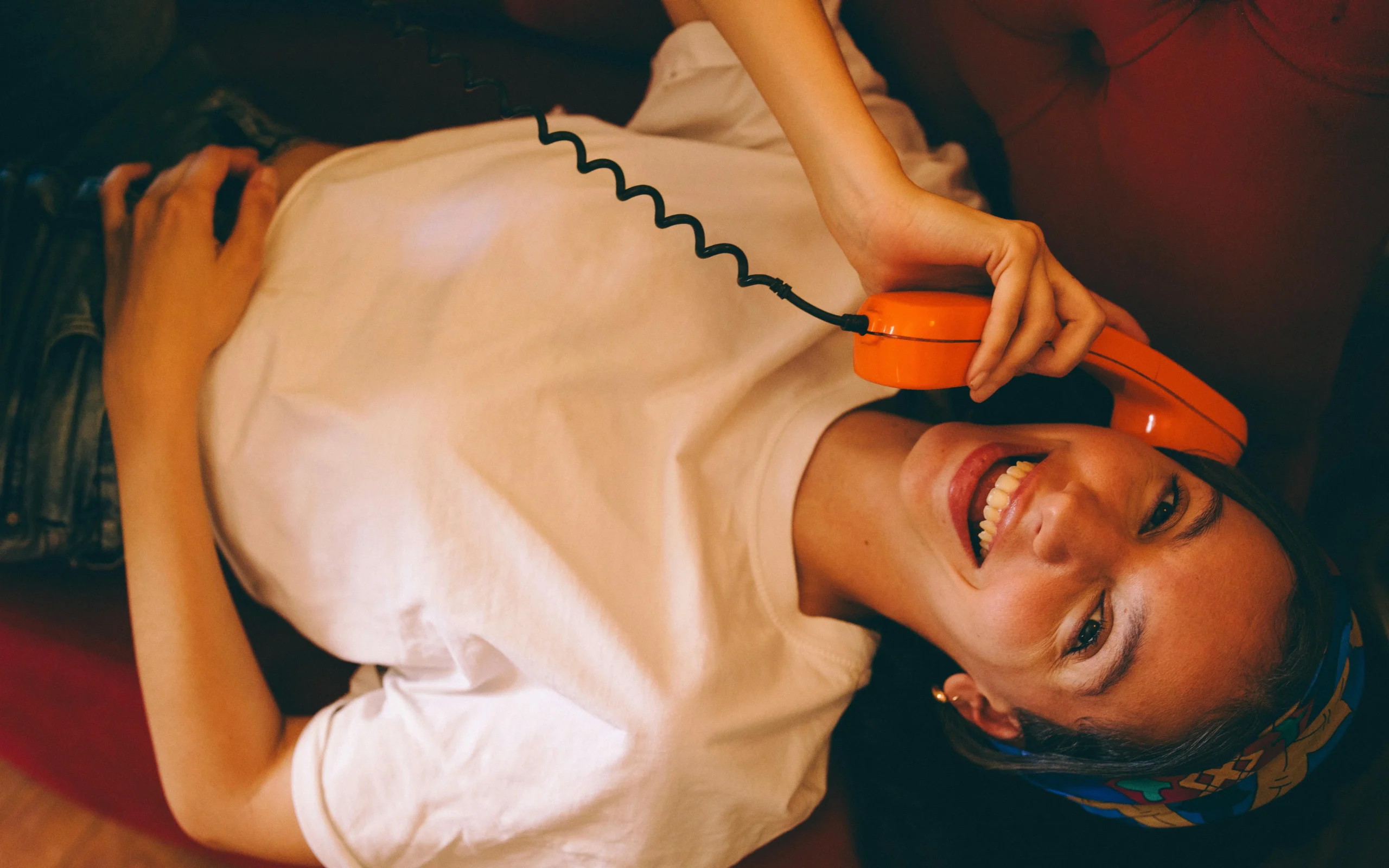 Woman laughing on a retro orange phone, hero image for the "one message, five ways" section of Carousel Post GPT