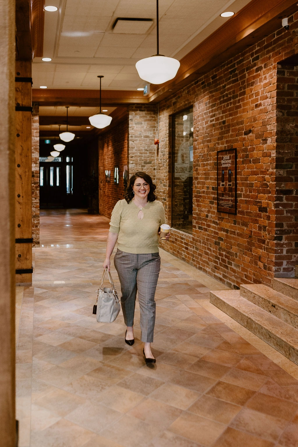 Erica Waddell, marketing consultant and founder of Post Road Marketing, walking through a historic brick hallway in Saint John, New Brunswick
