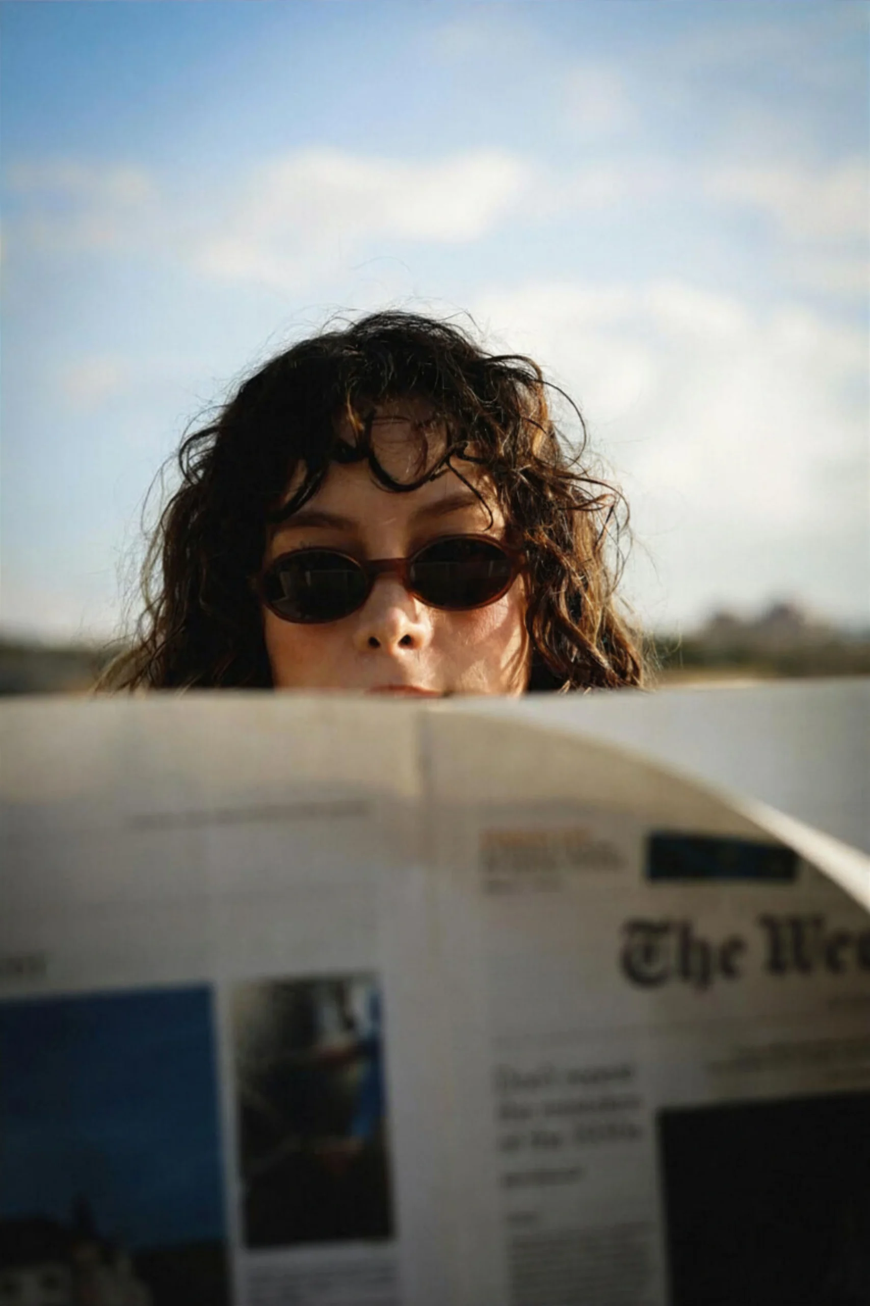 Woman in sunglasses reading the Weekly Route Planner newsletter outdoors