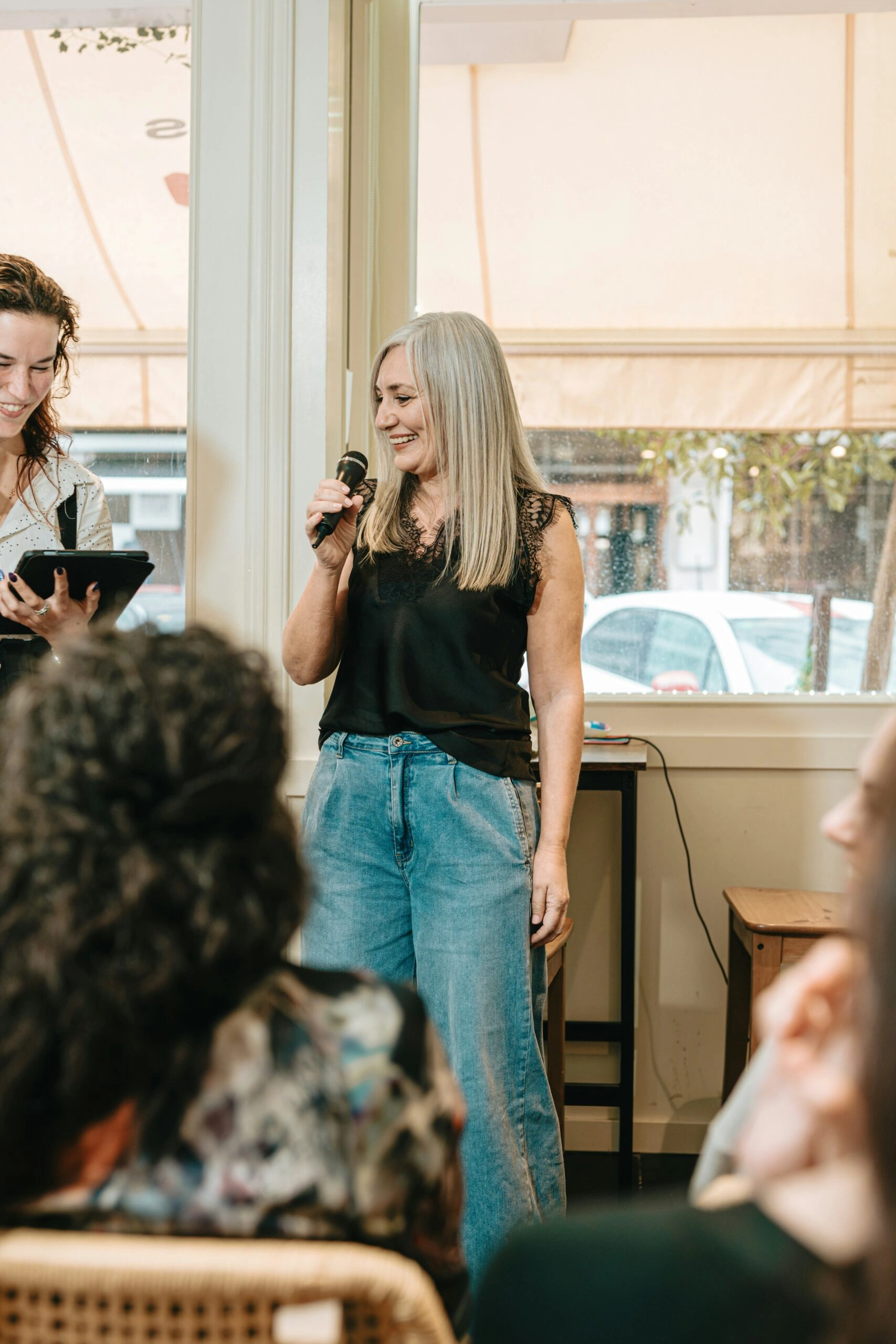 Woman speaking to a small gathered audience in a bright café setting