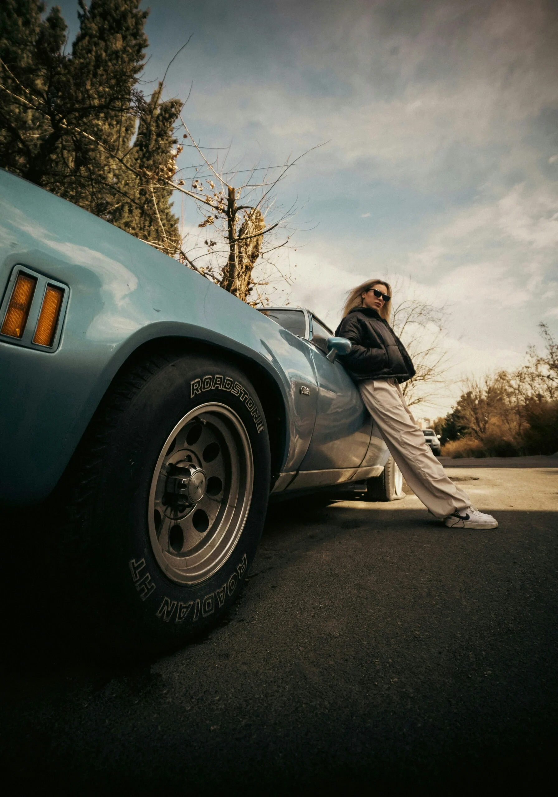 Woman leaning against a vintage car before a road trip — accompanying the FAQ section for the Build Your Custom GPT workshop