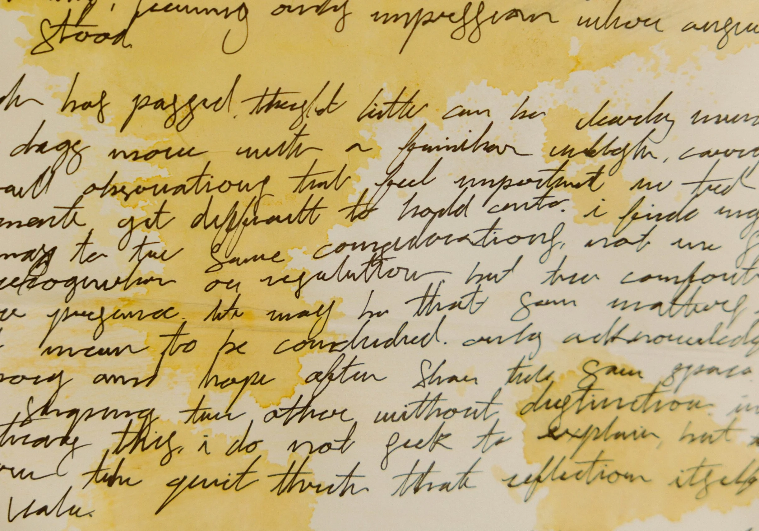 Close-up of cursive handwriting on aged paper with yellow water stains