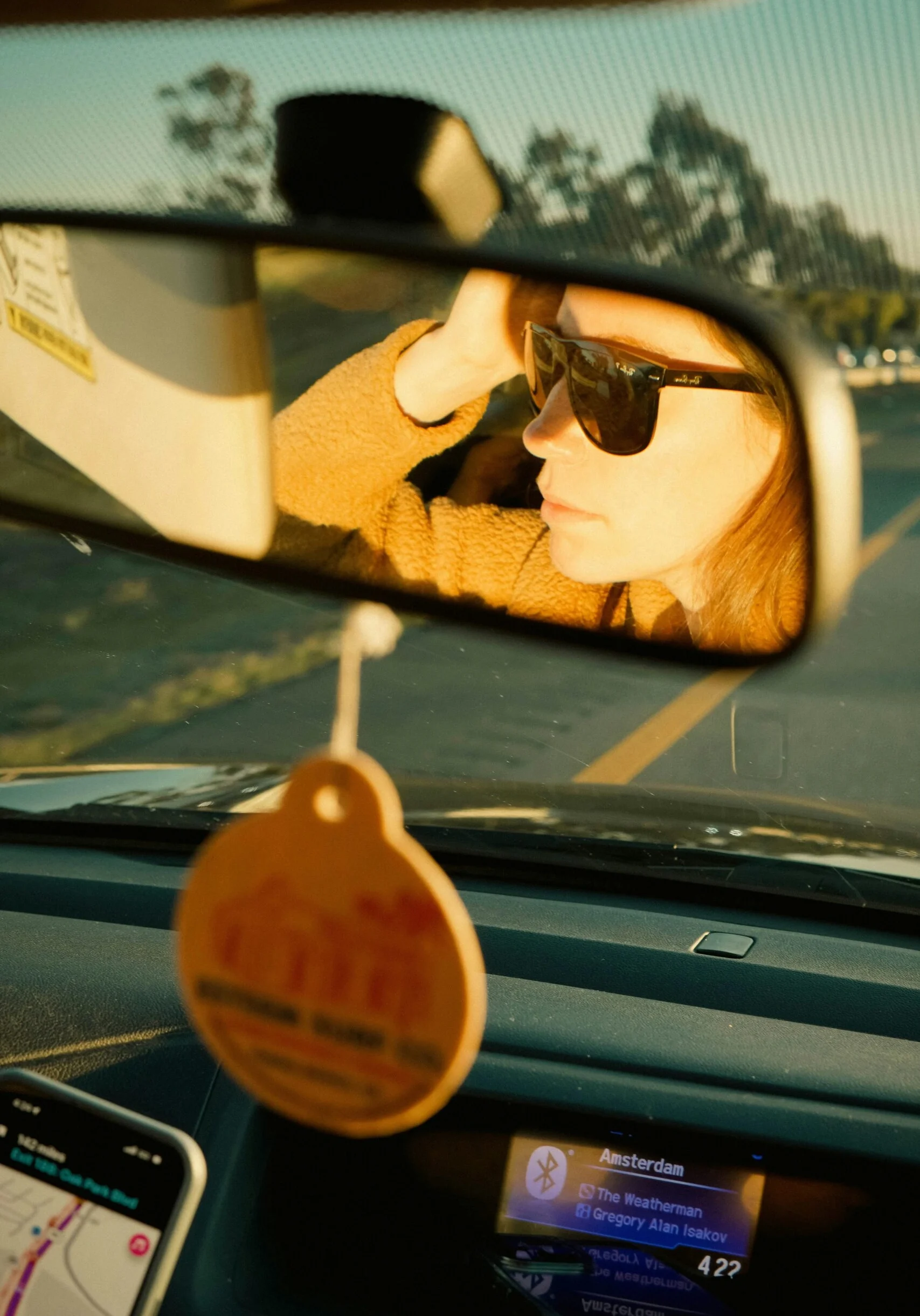 Woman reflected in a car rearview mirror on a road trip, representing the journey of building a marketing foundation with the ROAD Method